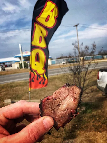 Highport BBQ Sign and Brisket piece in fingers.